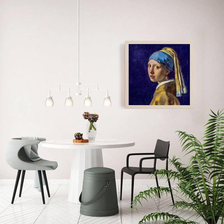 Geborduurd kunstwerk Meisje met de Parel van Vermeer ingelijst aan de muur boven een stijlvolle eetkamersetting. Perfect voorbeeld van hoe het borduurpakket als decoratief pronkstuk gebruikt kan worden.